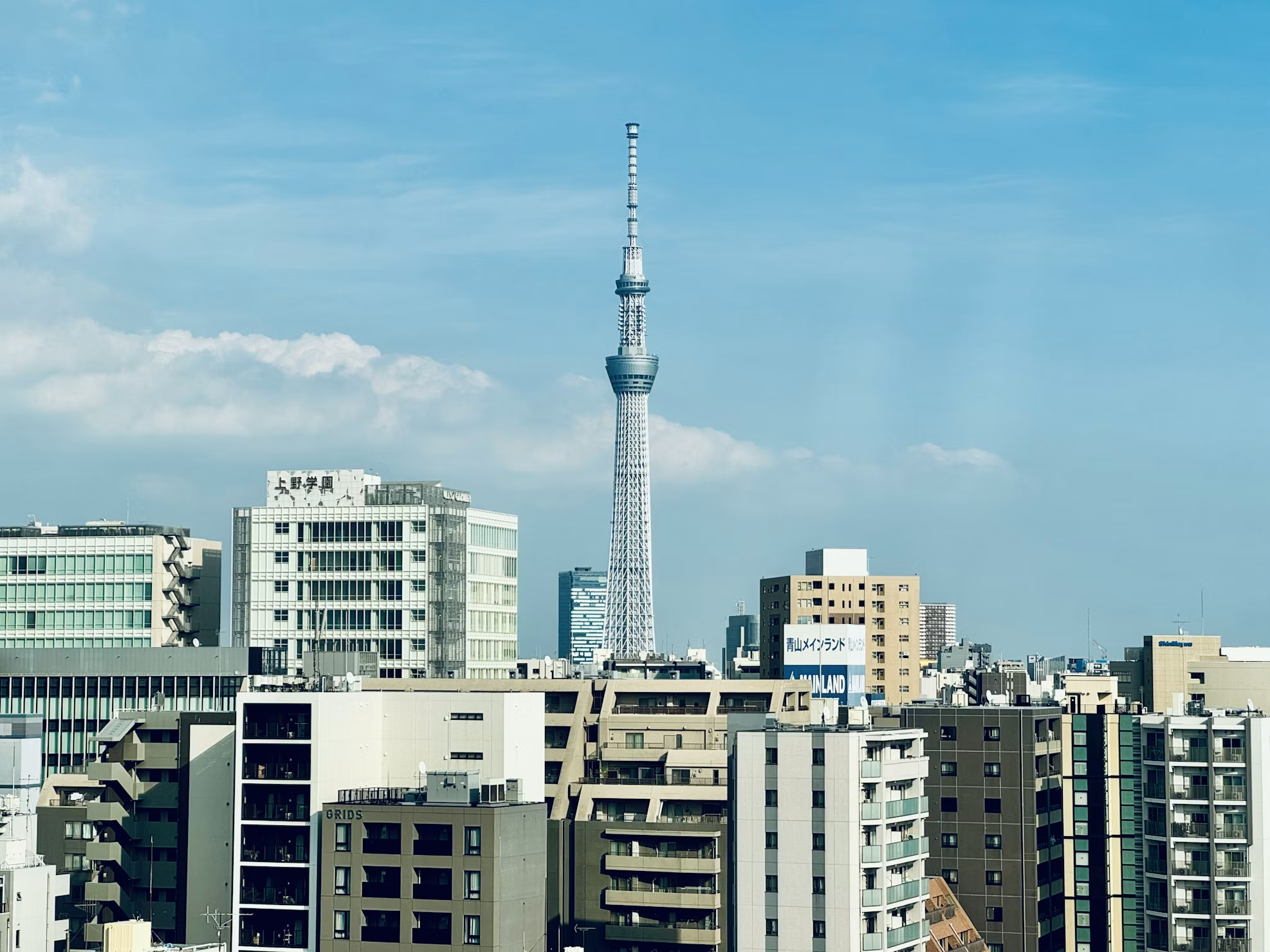 Tall tower stands above cityscape under blue sky.